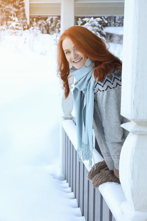 Beautiful young woman looking out from wooden gazebo on snowy day outdoors. Winter vacationの写真素材