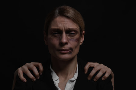 Kidnapper near scared woman with bruises on dark background. Hostage