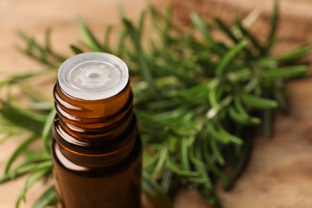 Bottle with essential oil and fresh rosemary against blurred background, closeup. Space for textの写真素材