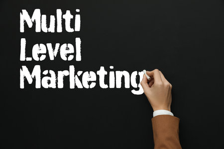 Woman writing text Multi Level Marketing with chalk on blackboard, closeupの写真素材