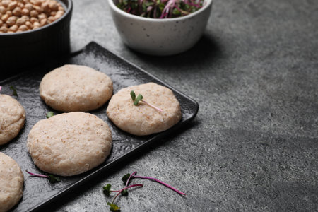 Raw vegan nuggets and spices on gray table, space for text