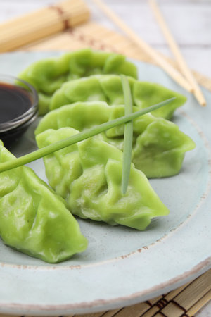 Delicious green dumplings (gyozas) and soy sauce on white bamboo mat, closeupの写真素材