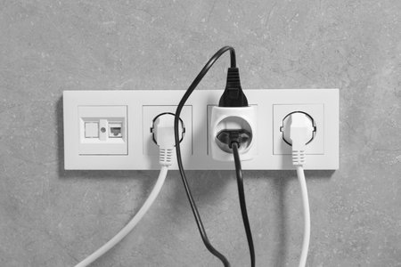 Many different electrical power plugs in sockets on gray wallの写真素材
