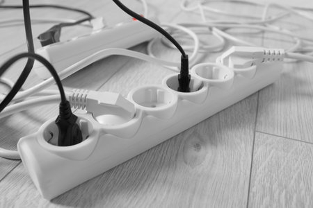 Power strip with different electrical plugs on white floor, closeupの写真素材
