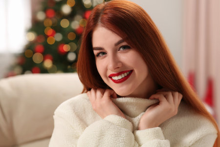 Beautiful young woman on sofa tree at home, space for text. Celebrating Christmasの写真素材