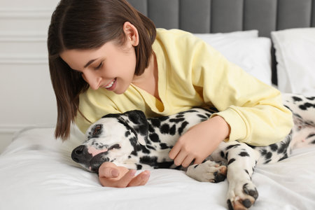 Beautiful woman with her adorable Dalmatian dog on bed at home. Lovely petの写真素材