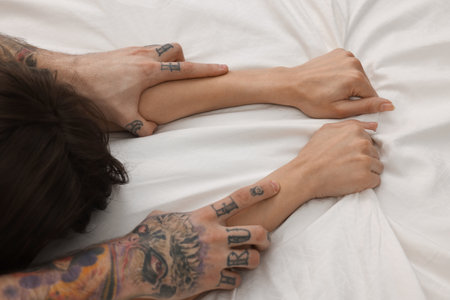 Passionate couple having sex on bed, closeup of handsの写真素材