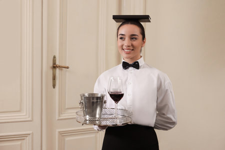 Woman with tray and book on head practicing good posture indoors, space for text. Professional butler coursesの写真素材