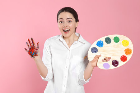 Woman with painted palm and palette on pink background. Young artistの写真素材