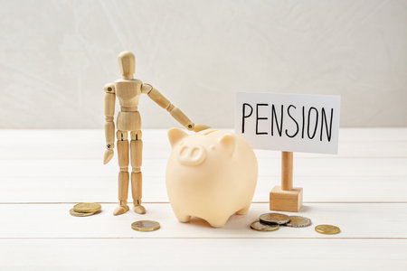 Pension savings. Piggy bank, coins and mannequin on white wooden tableの写真素材