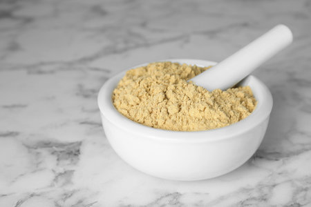 Mortar with aromatic mustard powder on white marble tableの写真素材
