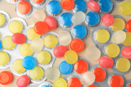 Blisters and many colorful cough drops on beige background, flat layの写真素材