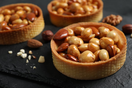 Tartlets with caramelized nuts on black table, closeup. Delicious dessertの写真素材