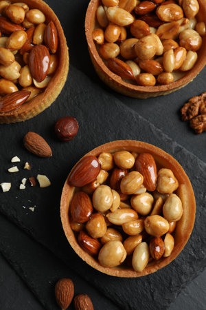 Tartlets with caramelized nuts on black table, top view. Delicious dessertの写真素材