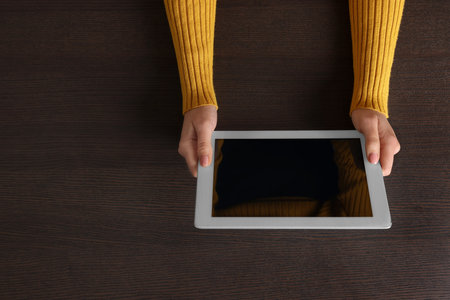 Woman working with tablet at wooden table, top view. Space for textの写真素材