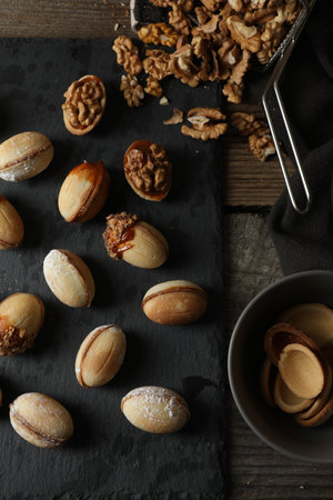 Freshly baked homemade walnut shaped cookies and nuts on wooden table, flat lay