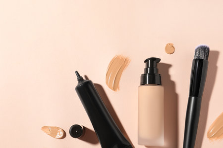 Liquid foundations, swatches and makeup brush on beige background, flat lay. Space for textの写真素材