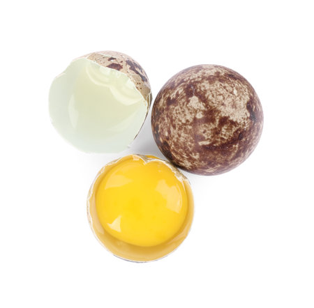 Whole and cracked quail eggs on white background, top view