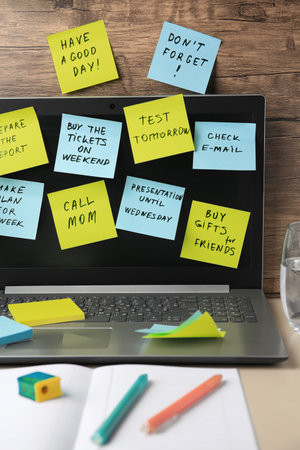 Many different reminder notes and laptop on table against wooden background
