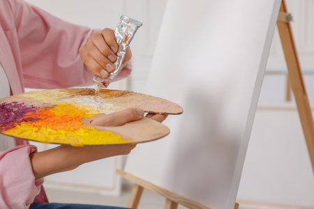 Woman mixing paints on palette near easel in studio, closeupの写真素材