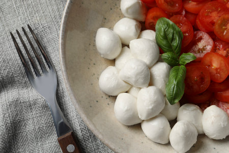 Delicious mozzarella balls, tomatoes and fork on table, flat layの写真素材