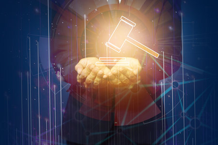 Auction. Businessman holding glowing illustration of sound block and gavel against blue background, closeupの写真素材