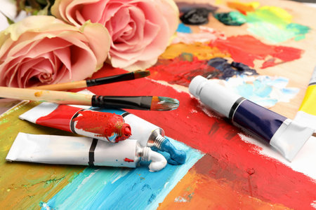 Tubes of colorful oil paints, flowers and brushes on canvas with abstract paintingの写真素材