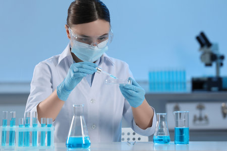 Scientist dripping liquid from pipette into petri dish in laboratory