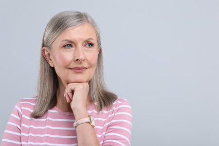 Portrait of beautiful senior woman on light gray background. Space for text
