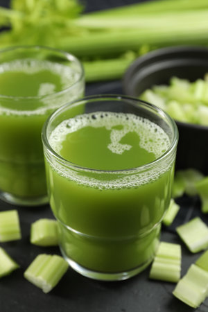 Glasses of delicious celery juice and vegetables on black table, closeupの写真素材