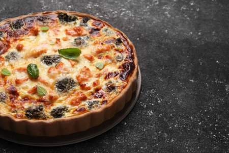 Delicious homemade quiche with salmon and broccoli on black table, space for textの写真素材