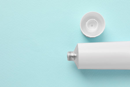 Open tube of ointment on light blue background, flat lay. Space for textの写真素材