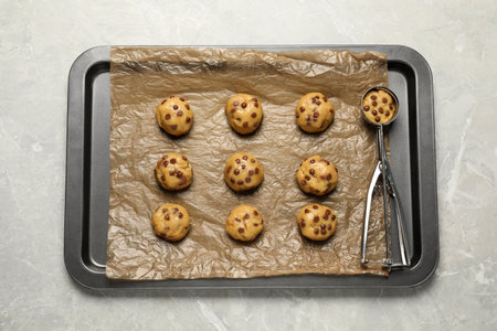 Tray with uncooked chocolate chip cookies on light gray table, top view