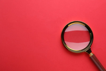 Magnifying glass on red background, top view. Space for textの写真素材