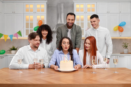 Happy friends with tasty cake celebrating birthday in kitchen