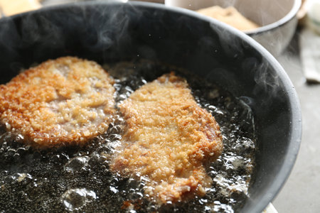 Cooking schnitzels in frying pan, closeup view