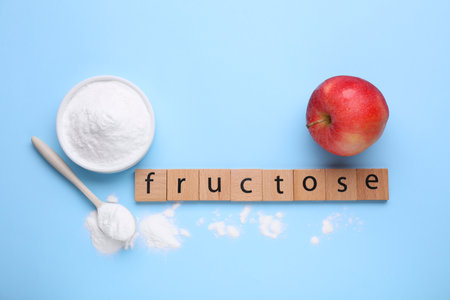 Word Fructose made of wooden cubes, powder and fresh apple on light blue background, flat layの写真素材