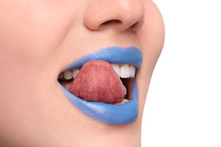 Woman with blue lipstick showing her tongue on light background, closeup. Space for textの写真素材