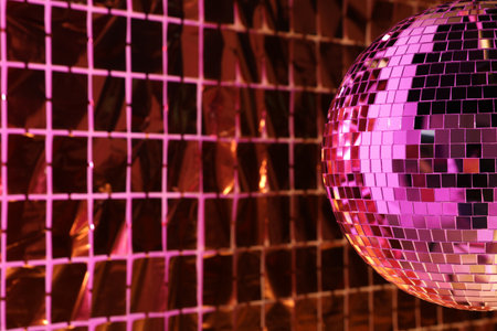 Shiny disco ball against foil party curtain under pink light, space for textの写真素材