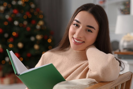 Christmas mood. Portrait of smiling woman with book indoorsの写真素材