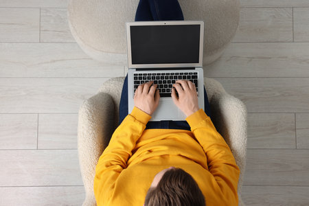 Man working with laptop in armchair, top viewの写真素材