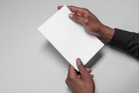 African American man holding sheet of paper on white background, closeup. Mockup for designの写真素材