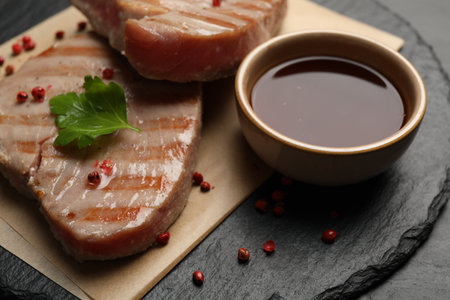 Delicious tuna steaks with sauce, parsley and spices on table, closeupの写真素材