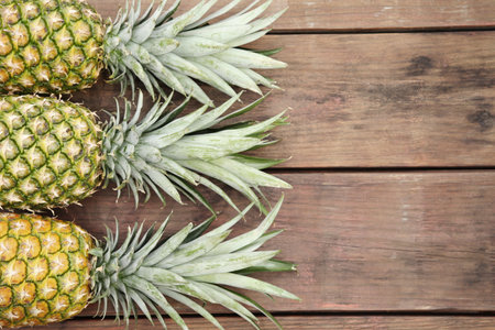 Delicious ripe pineapples on wooden table, flat lay. Space for textの写真素材