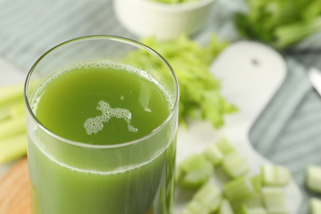 Glass of delicious celery juice and vegetables on wooden board, closeup. Space for textの写真素材