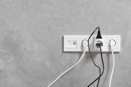 Many different electrical power plugs in sockets on gray wall, space for text