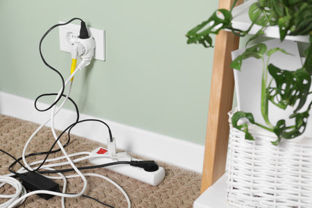 Different electrical plugs in socket and power strip on floor indoors