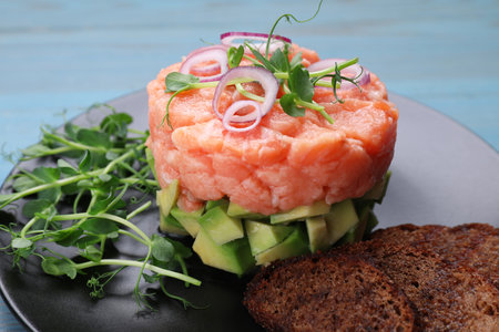 Tasty salmon tartare with avocado, microgreens and croutons on table, closeupの写真素材