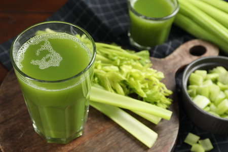Glasses of delicious celery juice and vegetables on wooden board, closeup. Space for textの写真素材