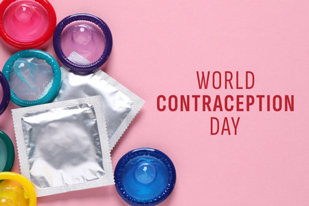 World contraception day. Many colorful condoms on pink background, flat layの写真素材